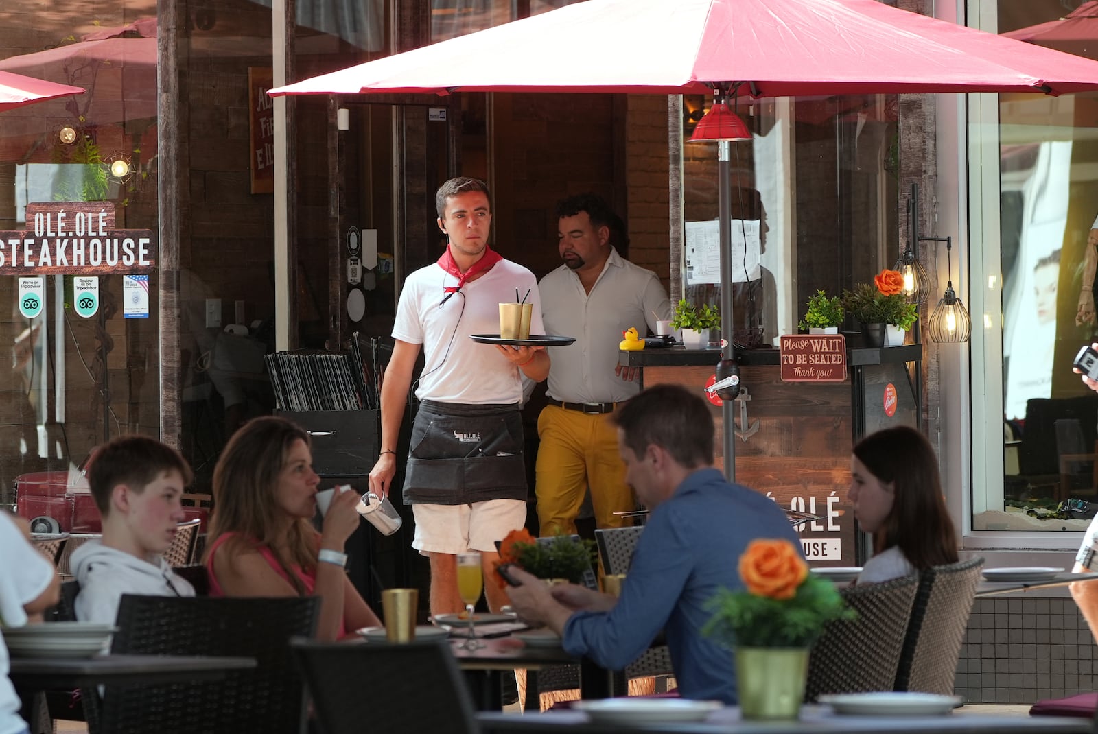 FILE - A waiter carries drinks, Friday, April 18, 2025, in Miami Beach, Fla. (AP Photo/Marta Lavandier, File)
