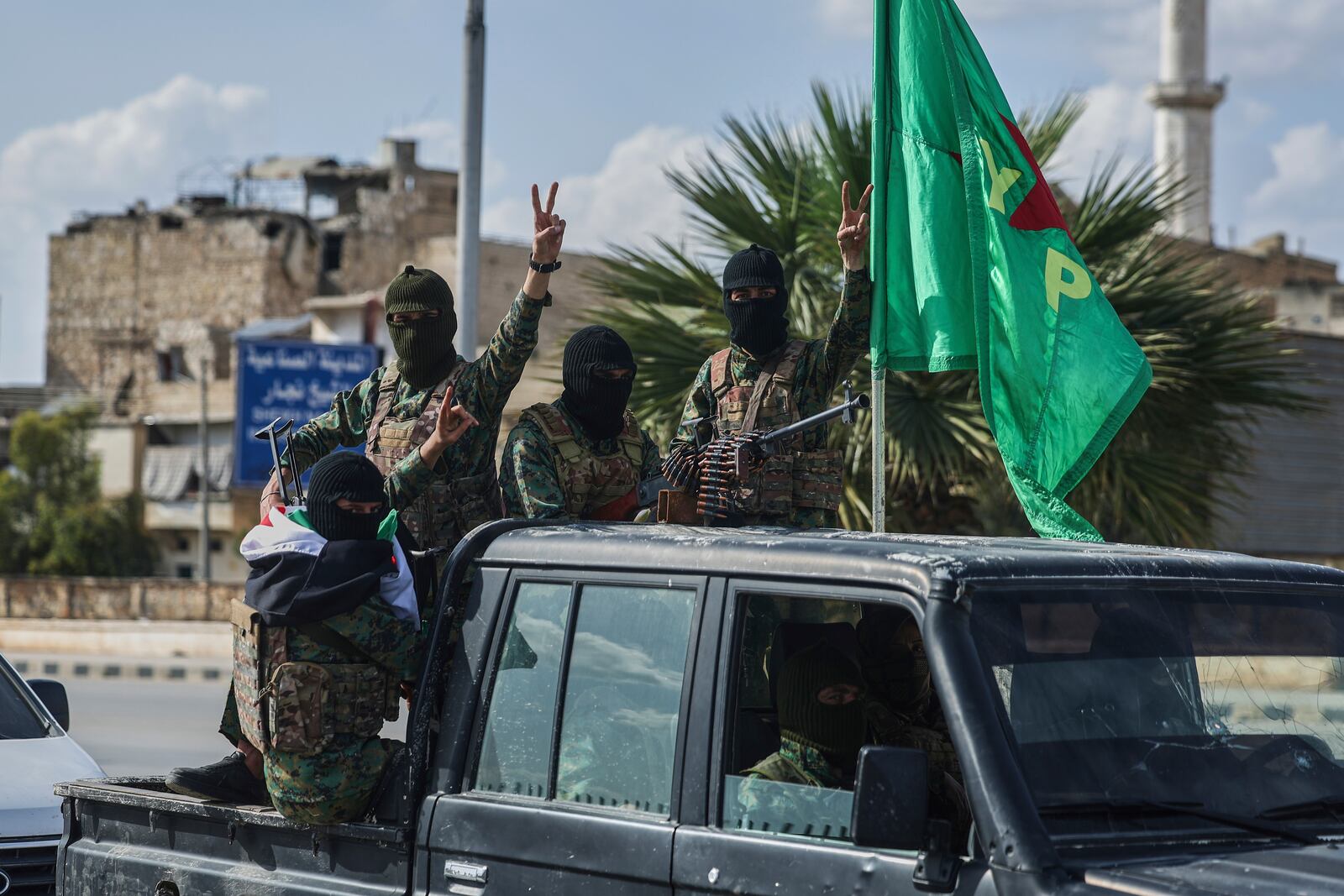 U.S.-backed Kurdish fighters flash victory signs, as they withdraw from two neighbourhoods in Syria's northern city of Aleppo as part of a deal with the Syrian central government, in Aleppo, Syria, Friday, April 4, 2025. (AP Photo/Ghaith Alsayed)