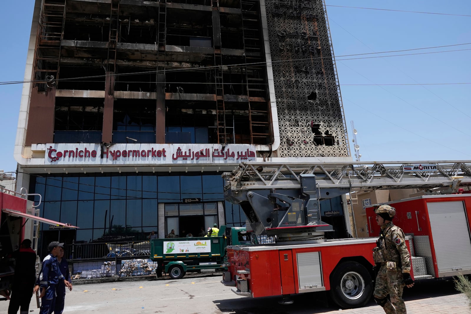 Firefighters gather in front of a burning hypermarket building in Kut, Iraq, Thursday, July 17, 2025. (AP Photo/ Hadi Mizban)