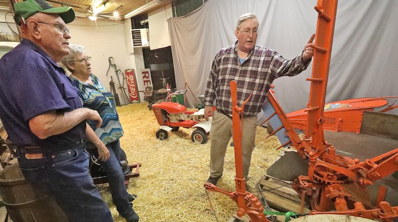 Bob Wood, left, and his wife, Sharon, talk with Dan Hearlihy about the antique Champion Reaper they had just delivered to him at his museum Tuesday. BILL LACKEY/STAFF