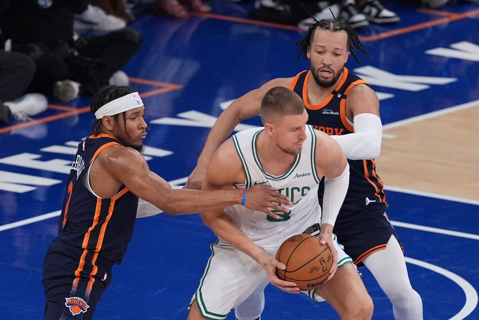 New York Knicks' Miles McBride, left, and Jalen Brunson, right, defend Boston Celtics' Kristaps Porzingis during the first half of Game 4 in the Eastern Conference semifinals of the NBA basketball playoffs Monday, May 12, 2025, in New York. (AP Photo/Frank Franklin II)