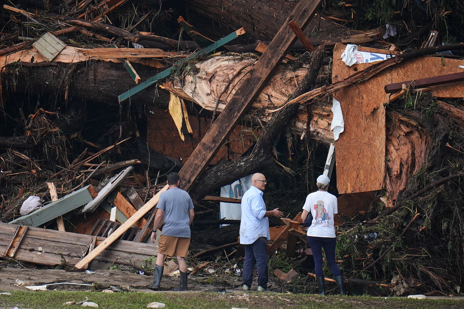 People look at debris on the banks of the Guadalupe River after a flash flood swept through the area Saturday, July 5, 2025, in Hunt, Texas. (AP Photo/Julio Cortez)