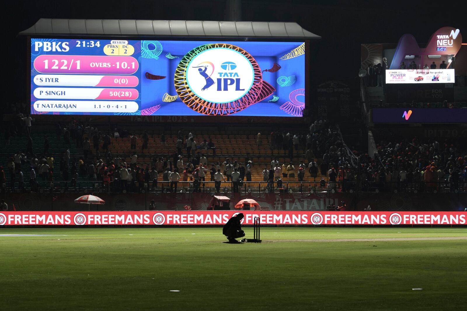 A worker removes the equipment placed next to the stumps after the authorities asked to evacuate the stadium during the Indian Premier League cricket match between Punjab Kings and Delhi Capitals at Himachal Pradesh Cricket Association Stadium in Dharamshala, India, Thursday, May 8, 2025. (AP Photo/Ashwini Bhatia)