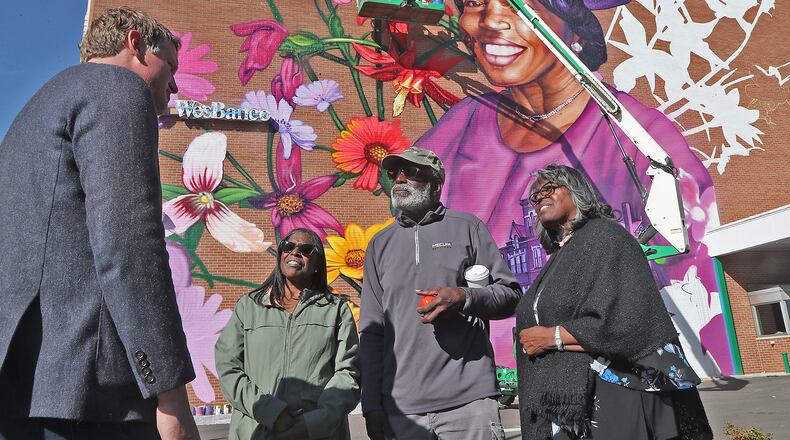 Kevin Rose, historian with the Turner Foundation, talks with the nieces and nephew of Hattie Moseley following a dedication of the mural in her honor Tuesday, Oct. 11, 2022. Hattie's family members, from left, Diantha Applin, Booker Wooten and Shirley Y. Harris said it was an honor to have their aunt represented in the mural. Artist Gaia is finishing the mural using a lift in the background. BILL LACKEY/STAFF