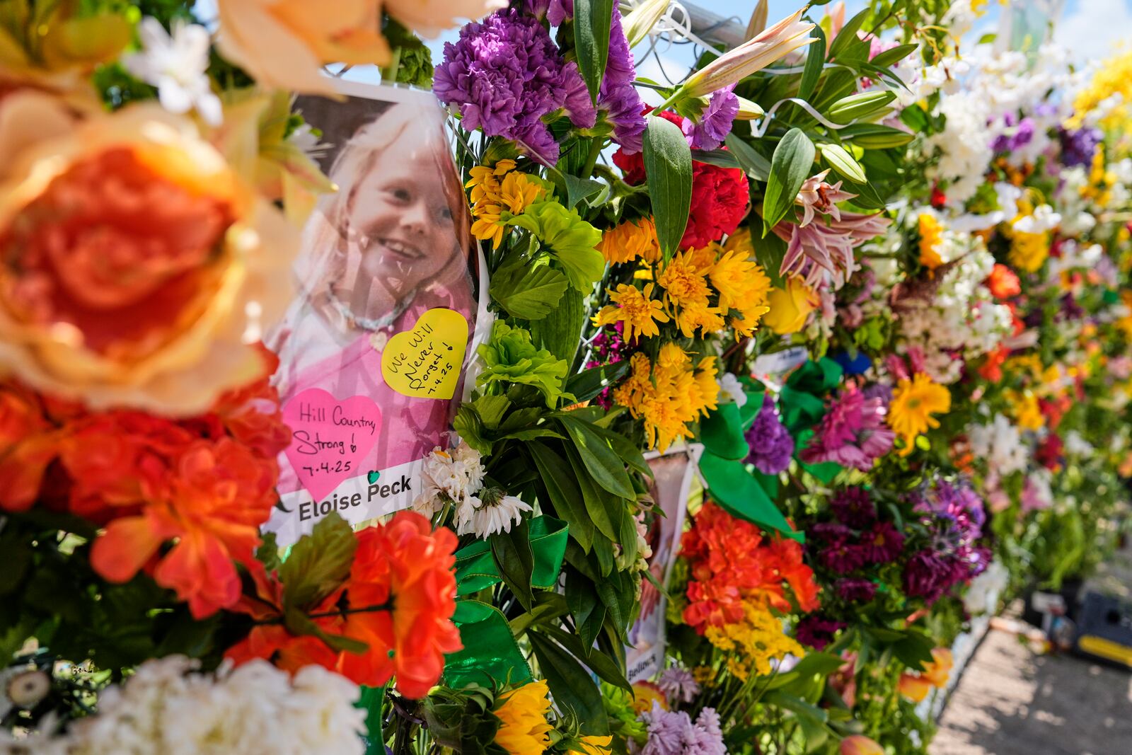 Photographs of flood victims are displayed on a memorial wall in Kerrville, Texas, Thursday, July 10, 2025. (AP Photo/Ashley Landis)