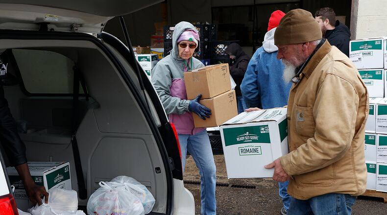 Volunteers at the Second Harvest Food Bank load the trunk of a car with food during a food distribution last month. BILL LACKEY/STAFF