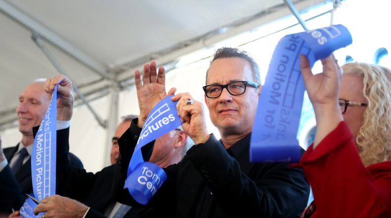Actor Tom Hanks holds up a piece of cut ribbon after participating in a ribbon cutting for the new Tom Hanks Center for Motion Pictures at Wright State University Tuesday. LISA POWELL / STAFF