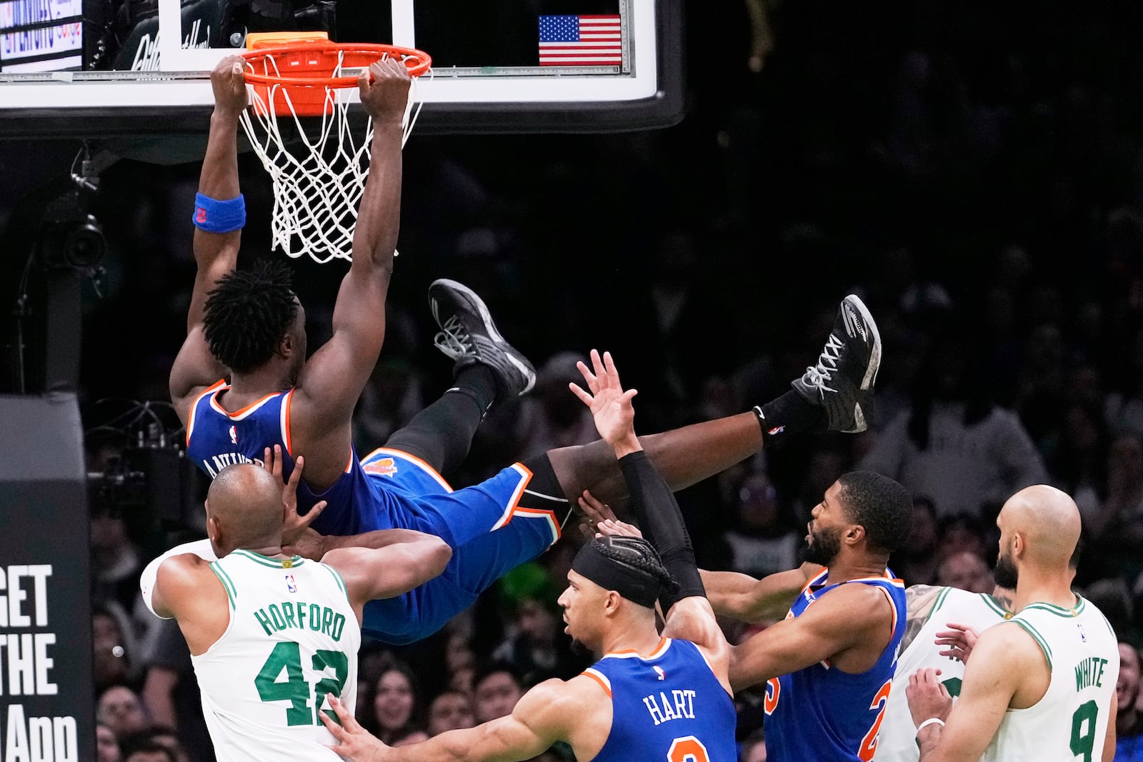 New York Knicks forward OG Anunoby, top, hangs from the rim after dunking against the Boston Celtics during the second half of Game 1 of an NBA basketball second-round playoff series Monday, May 5, 2025, in Boston. (AP Photo/Charles Krupa)