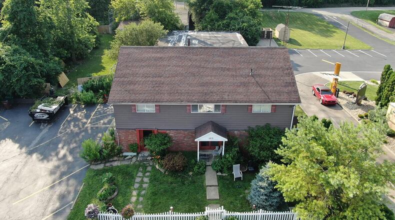The front of the property features a white picket fence, mature trees and landscaping and a covered front porch. There are two separate entrances on the front. The home has 5 bedrooms and 2 full and 3 half baths. CONTRIBUTED PHOTO