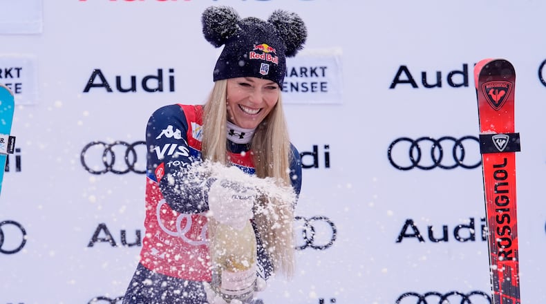 United States' Lindsey Vonn sprays sparkling wine as she celebrates on podium after winning an alpine ski, women's World Cup downhill, in Zauchensee, Austria, Saturday, Jan. 10, 2026. (AP Photo/Giovanni Auletta)