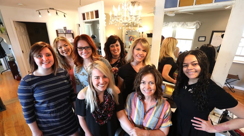 Tonya Roberdz, seated, is surrounded by her staff at Dezigns by Tonya Hair Salon in Enon Thursday, April 12, 2018. Tonya was named to the BBB’s Top 25 Women to Watch List.