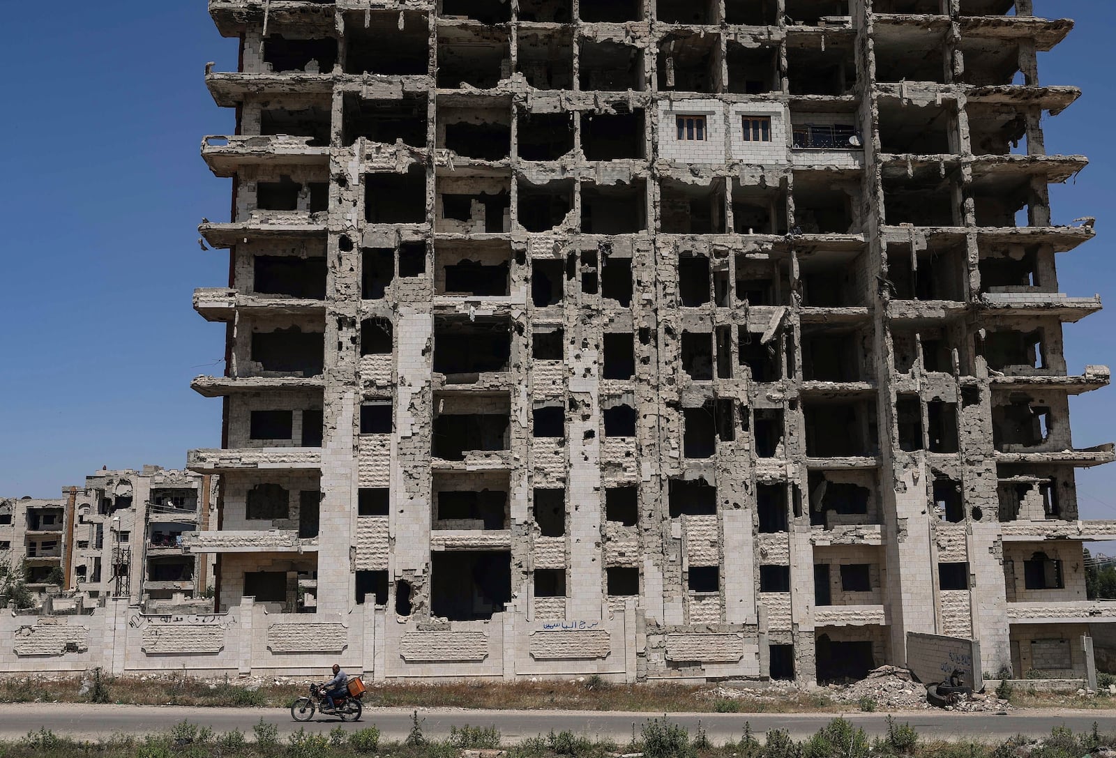 A restored apartment, top center, can be seen in an otherwise severely damaged apartment building in the Al-Waer neighborhood of Homs, Syria, Tuesday, May 13, 2025. (AP Photo/Ghaith Alsayed)