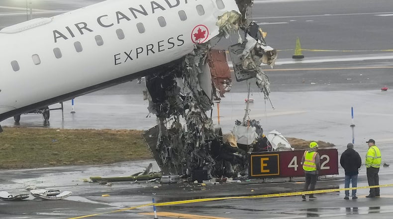 Officials investigate the site, Monday, March 23, 2026, where an Air Canada jet came to rest after colliding with a Port Authority firetruck at LaGuardia Airport, shortly after landing Sunday night in New York. (AP Photo/Seth Wenig)
