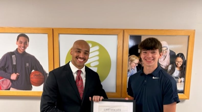 Cooper Johnson (right), a graduate of the Global Impact STEM Academy Class of 2023, was awarded the first Waklatsi Service Scholarship, which was established this year by GISA alumnus and current Clark County Sheriff's Deputy Kordell Waklatsi (left), with a picture behind him of when he was a freshman student. Contributed