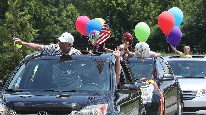 Family members wave to residents at Wooded Glen Senior Living Friday during a parade of decorated cars, German Township fire trucks and even a horse. The residents have had limited contact with their loved ones since the corona virus quarantine started and the parade was meant to cheer up the residents and their families. BILL LACKEY/STAFF