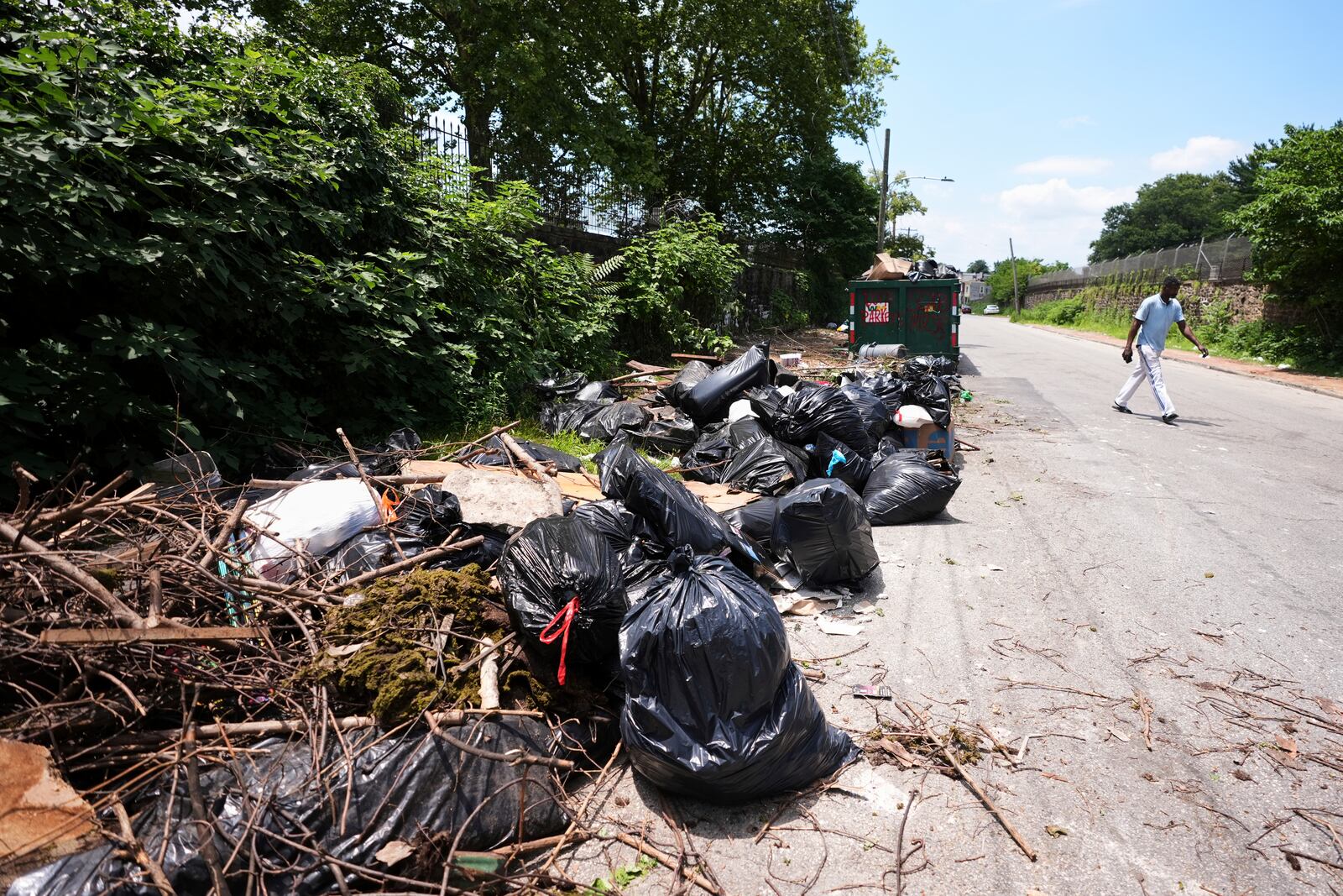 A man walks past a garbage collection site, Wednesday, July 9, 2025, in Philadelphia. (AP Photo/Matt Slocum)