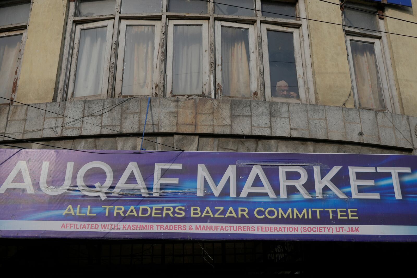 A man looks from a window near the Auqaf Market in Srinagar, Indian controlled Kashmir, Wednesday, April 2, 2025. (AP Photo/Mukhtar Khan)