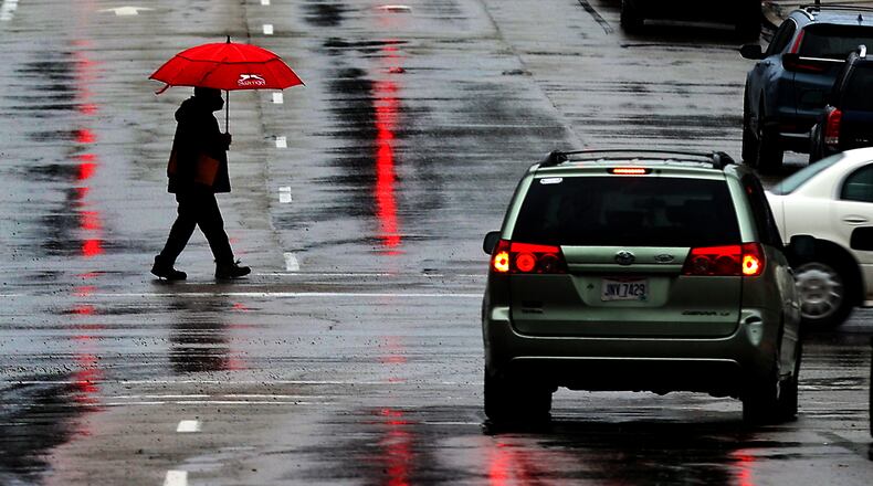 A man with a red umbrella matches the red traffic lights reflected on the wet roadway Feb. 22. Heavy rain drenched the area forcing some roads to be closed. BILL LACKEY/STAFF
