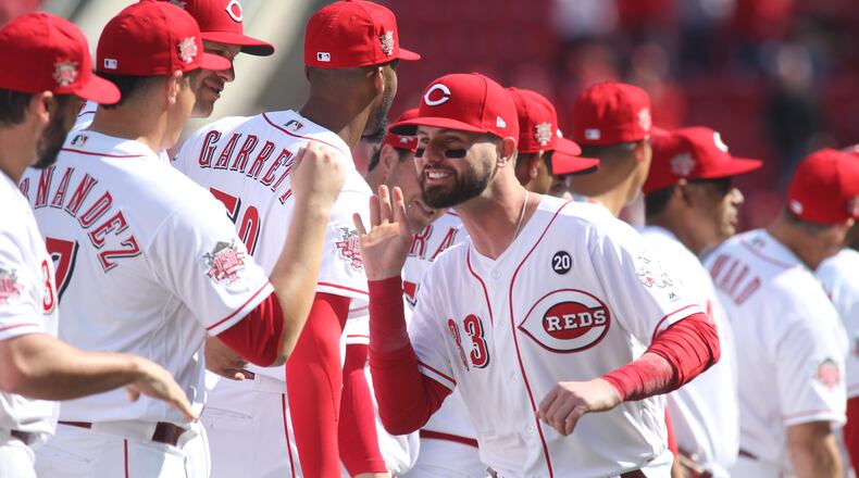 The Reds’ Jesse Winker slaps hands with teammates before a game against the Pirates on Opening Day on Thursday, March 28, 2019, at Great American Ball Park in Cincinnati.