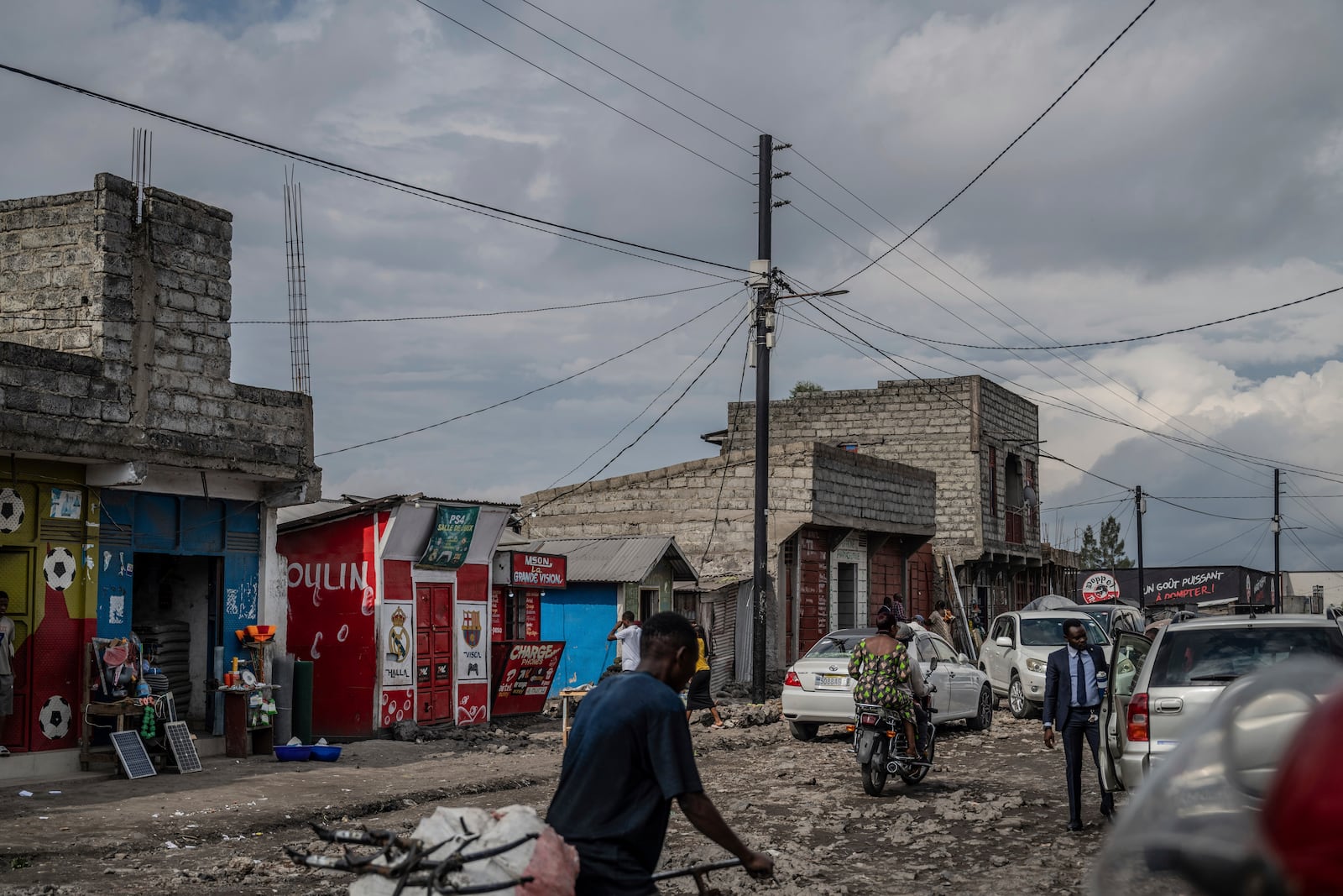 People move past an electricity pole bringing power from a Nuru solar farm in the Ndosho neighborhood of Goma, Congo, May 23, 2025. (AP Photo/Moses Sawasawa)
