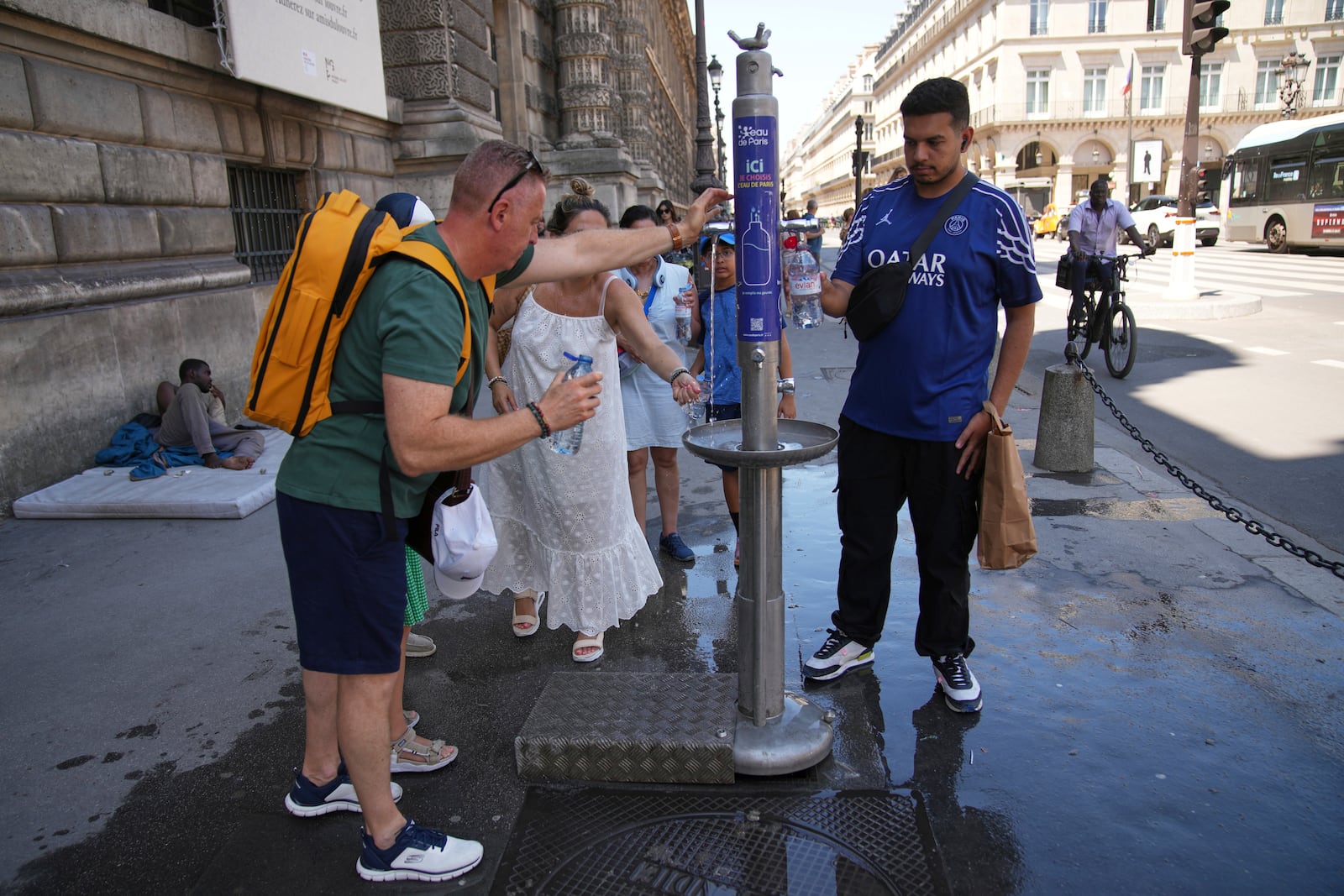 People use a street water fountain during a heat wave, Monday, June 30, 2025 in Paris. (AP Photo/Christophe Ena)