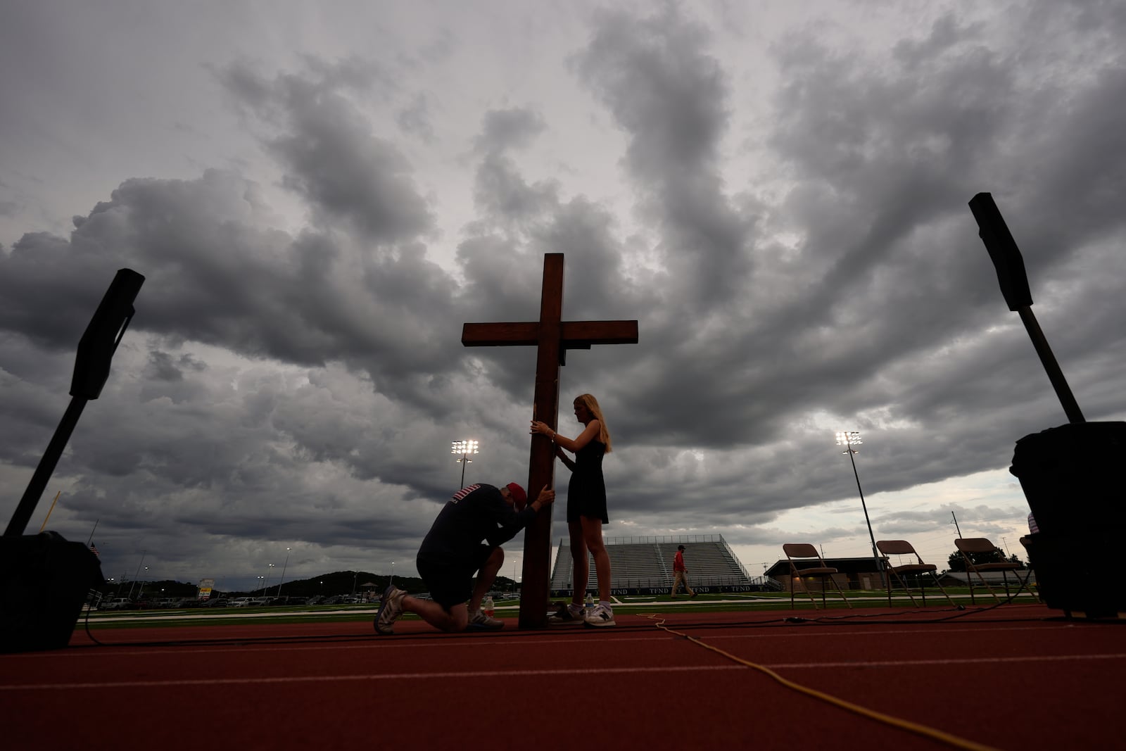Dan Beazley, of Michigan, left, reacts as he holds a large cross with Abigail Smithson during a vigil for flooding victims at Tivy Antler Stadium on Wednesday, July 9, 2025, in Kerrville, Texas. (AP Photo/Gerald Herbert)
