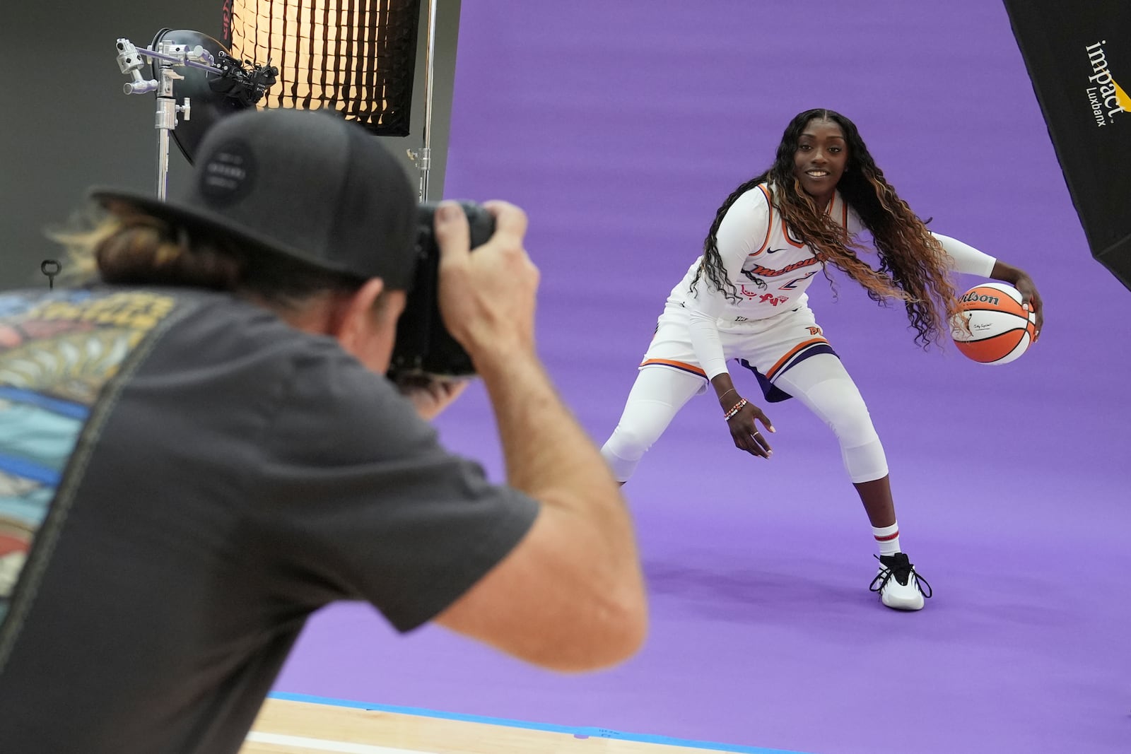 Phoenix Mercury guard-forward Kahleah Copper, right, dribbles the ball in front of team photographer Barry Gossage during a photo shoot at Mercury Media Day at the team's WNBA basketball training facility, Wednesday, April 30, 2025, in Phoenix. (AP Photo/Ross D. Franklin)