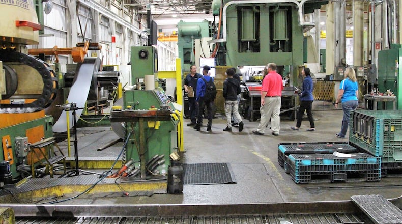 Kevin Smith, a training coordinator at Ohio Stamping and Machine, leads a group of Springfield High School students around the manufacturing floor on Friday.