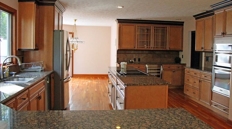 The open kitchen features granite countertops, hardwood floors, a center island and plenty of wood cabinetry.