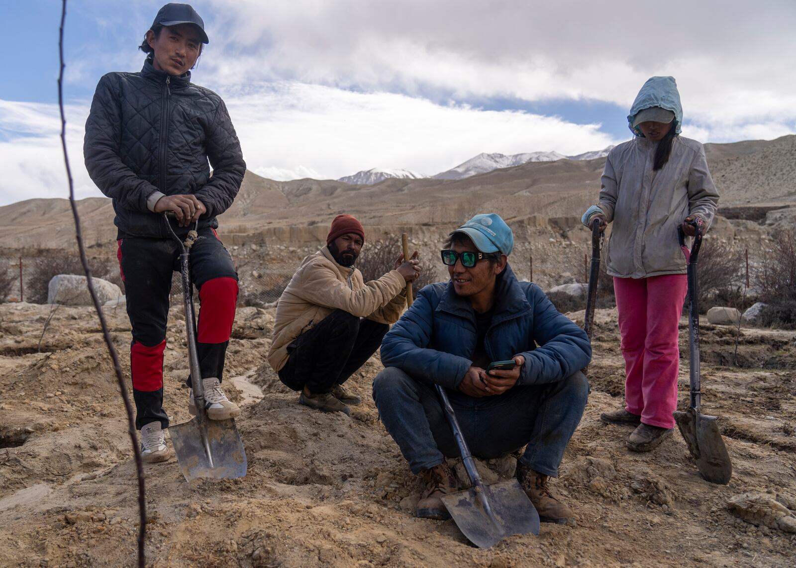 Villagers take a break while working in a field at the newly relocated settlement of the abandoned Samjung village in the Mustang region, 462 kilometers (288 miles) west of Kathmandu, Nepal, Friday, April 18, 2025. (AP Photo/Niranjan Shrestha)