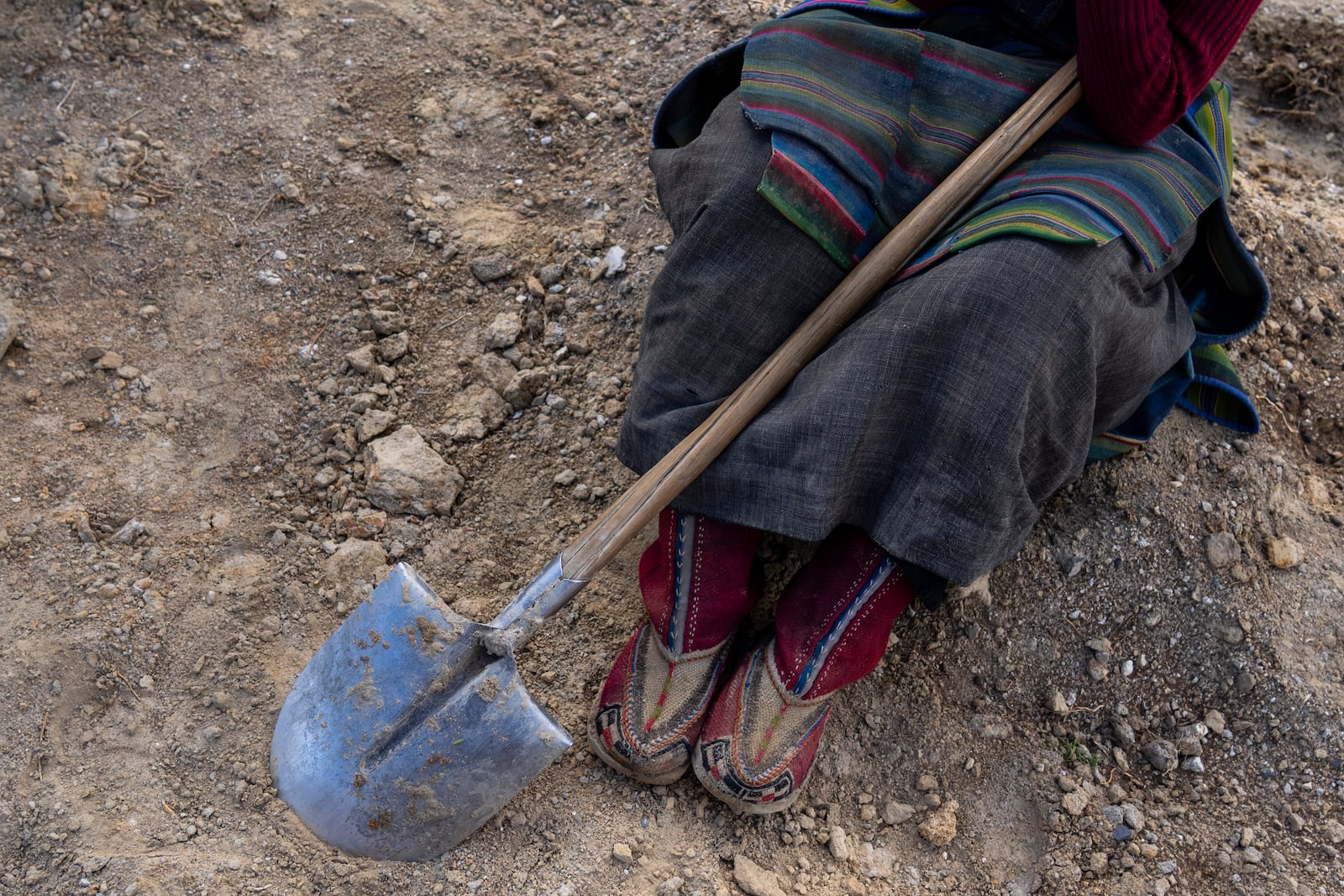 A woman takes a break from her work at the newly relocated settlement of the abandoned Samjung village in the Mustang region, 462 kilometers (288 miles) west of Kathmandu, Nepal, Friday, April 18, 2025. (AP Photo/Niranjan Shrestha)