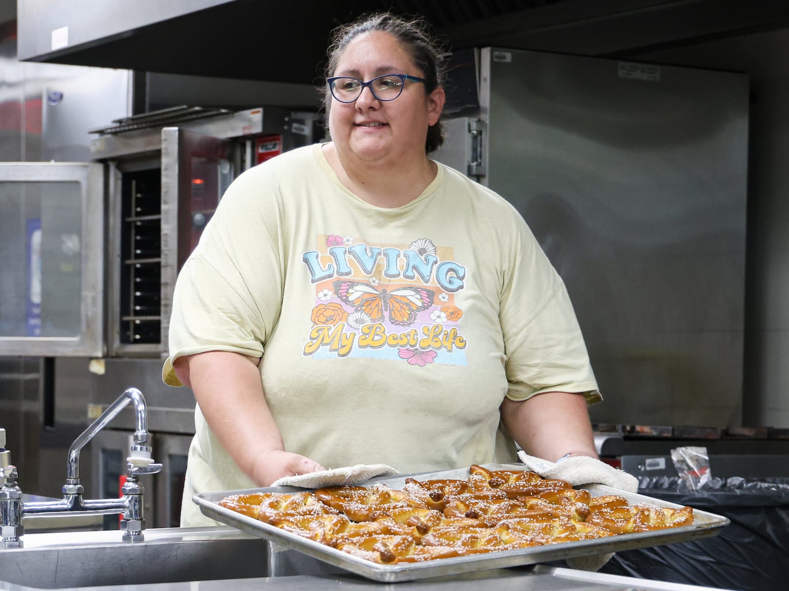 Kelsey Chaney, a food and nutrition supervisor, puts down a tray of pretzels during a summer lunch program organized by Kettering City Schools at Greenmont Elementary on Friday, Aug. 1. It was the final lunch for the program, which ran from June 2 to Aug. 1. BRYANT BILLING / STAFF