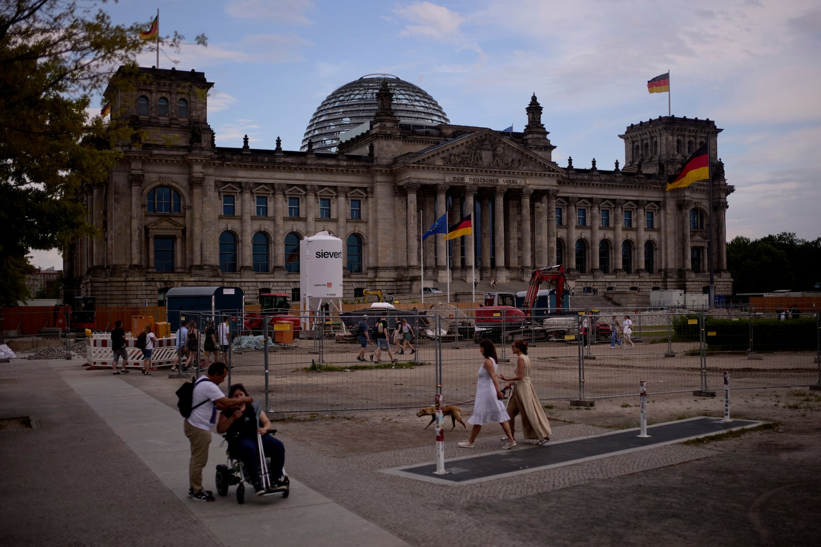 People walk in front of the Reichtag Building, in Berlin, Germany, Friday, May 2, 2025. (AP Photo/Markus Schreiber)