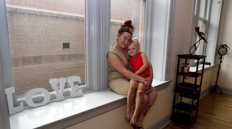 Brittany Jones sits with her daughter, Emma, in one of the windows in her new studio called, Make Our Photo Shine, in the Bushnell Building Friday. Bill Lackey/Staff