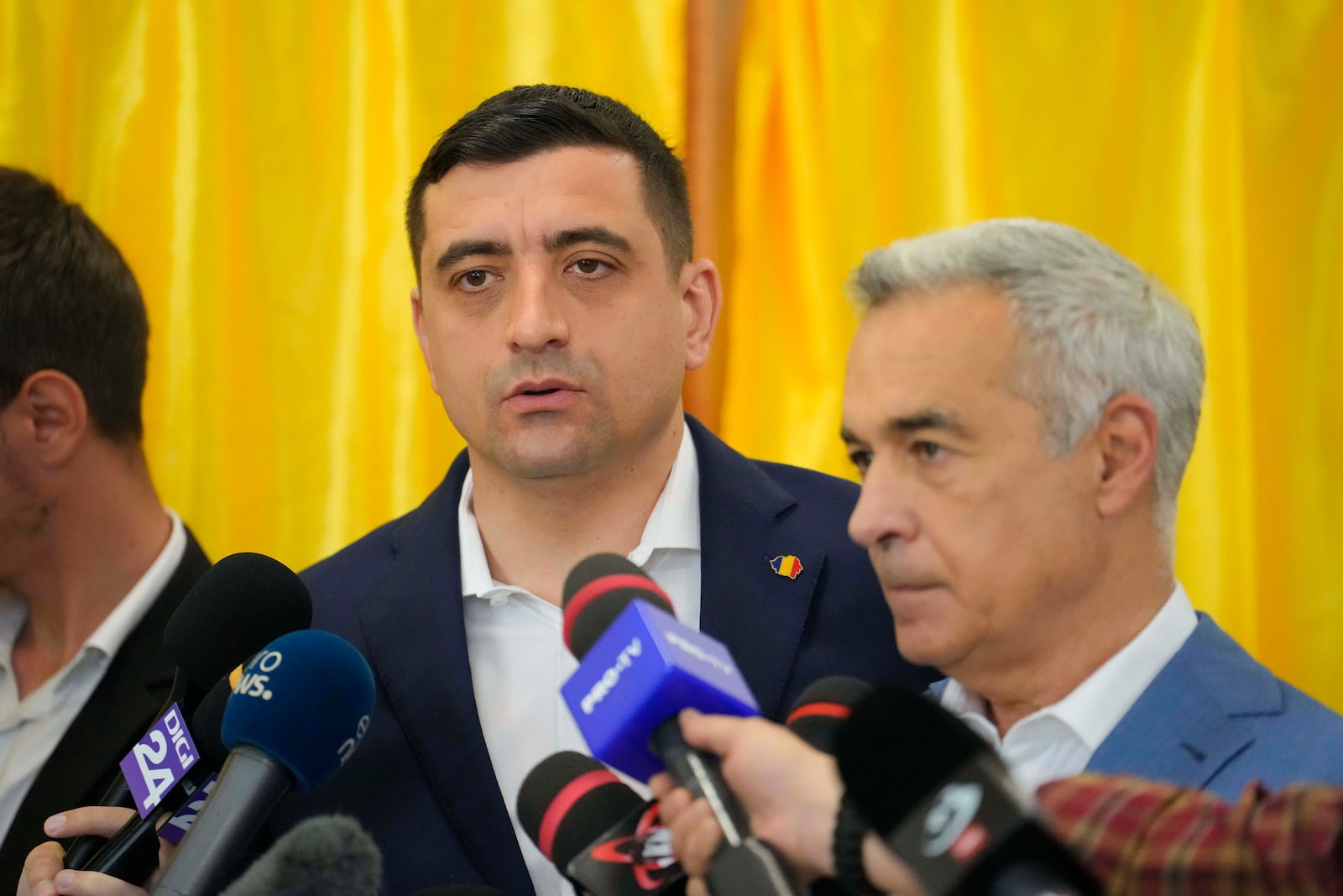 Presidential candidate George Simion, left, speaks to media alongside Calin Georgescu, winner of the first round of last year's annulled election, during first round of the presidential election redo in Bucharest, Romania, Sunday, May 4, 2025. (AP Photo/Vadim Ghirda)