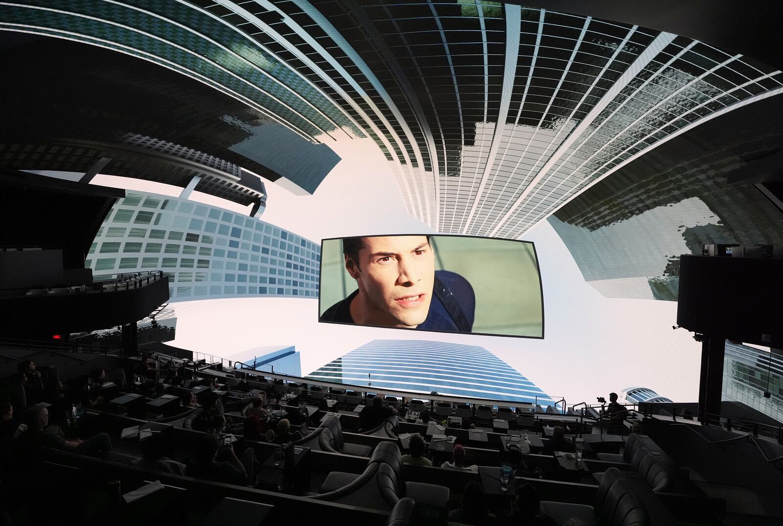 A scene from the film "The Matrix" is surrounded by immersive urban visuals during a screening of "The Matrix in Shared Reality" on Wednesday, May 28, 2025, at Cosm Los Angeles in Inglewood, Calif. (AP Photo/Chris Pizzello)