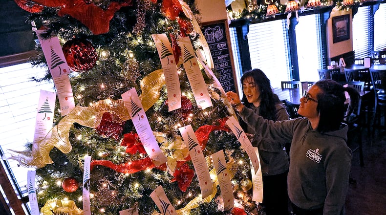 Alexis Hanson, left, and Johnny Gibson, both waitresses at O'Conners Irish Pub, look over the tags on the Salvation Army Angel Tree Wednesday, Nov. 16, 2022. BILL LACKEY/STAFF