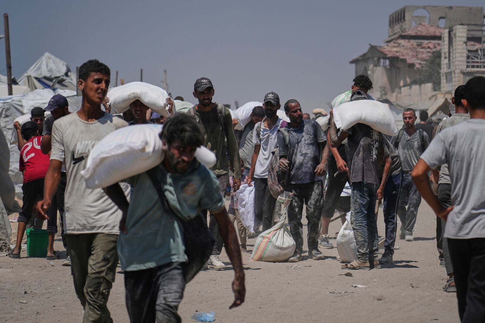 Palestinians carry sacks of flour unloaded from a humanitarian aid convoy that reached Gaza City from the northern Gaza Strip, Sunday, July 27, 2025. (AP Photo/Abdel Kareem Hana)