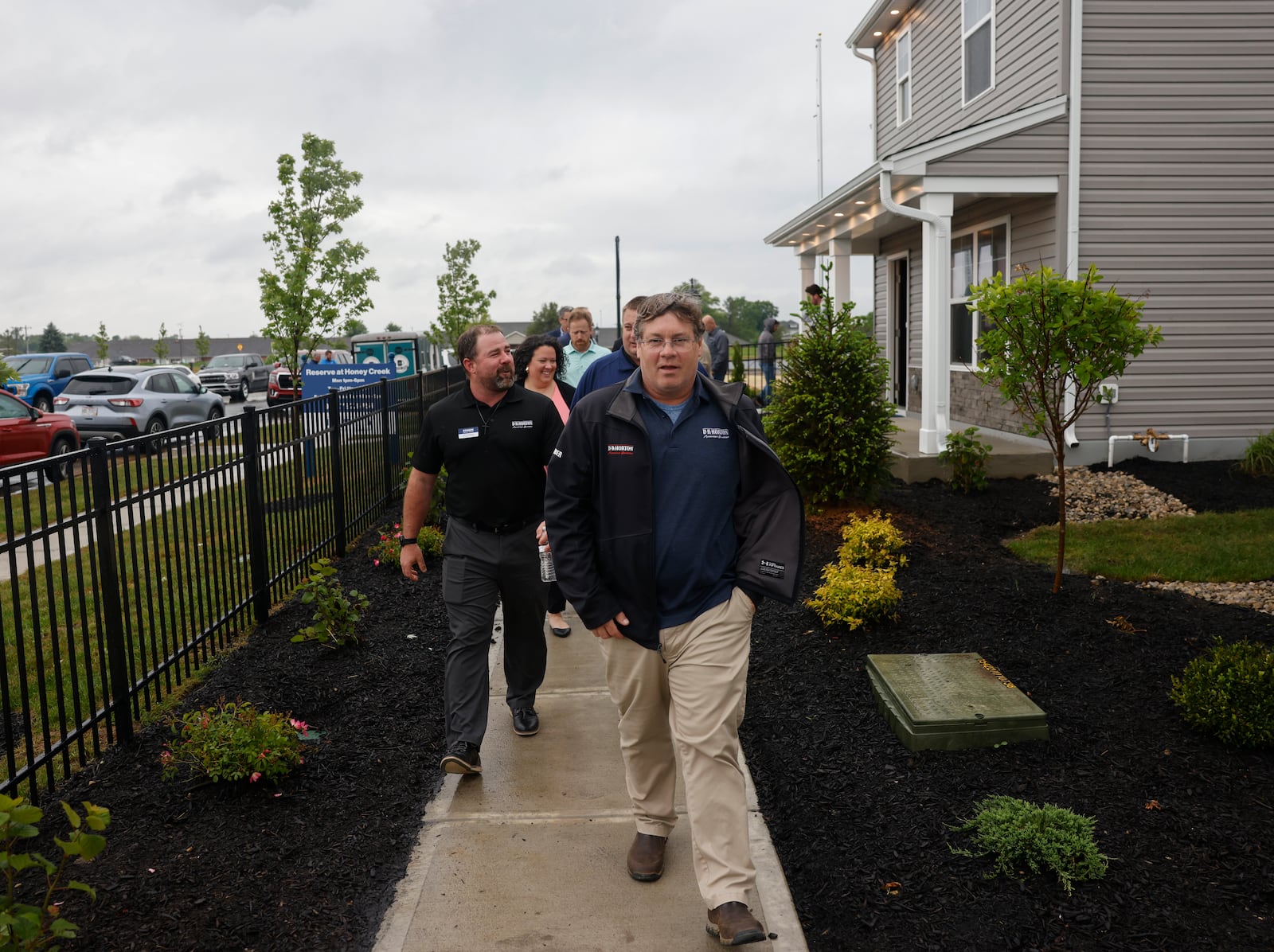 D.R. Horton project manager Greg Drown, front, walks with a group to see a new home during the grand opening at Reserve at Honey Creek on Tuesday, May 20, 2025, in New Carlisle. JOSEPH COOKE/STAFF