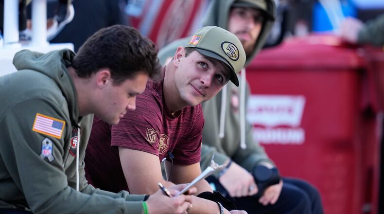 Injured San Francisco 49ers quarterback Brock Purdy, middle, sits on the bench during the first half of an NFL football game against the Los Angeles Rams in Santa Clara, Calif., Sunday, Nov. 9, 2025. (AP Photo/Godofredo A. Vásquez)