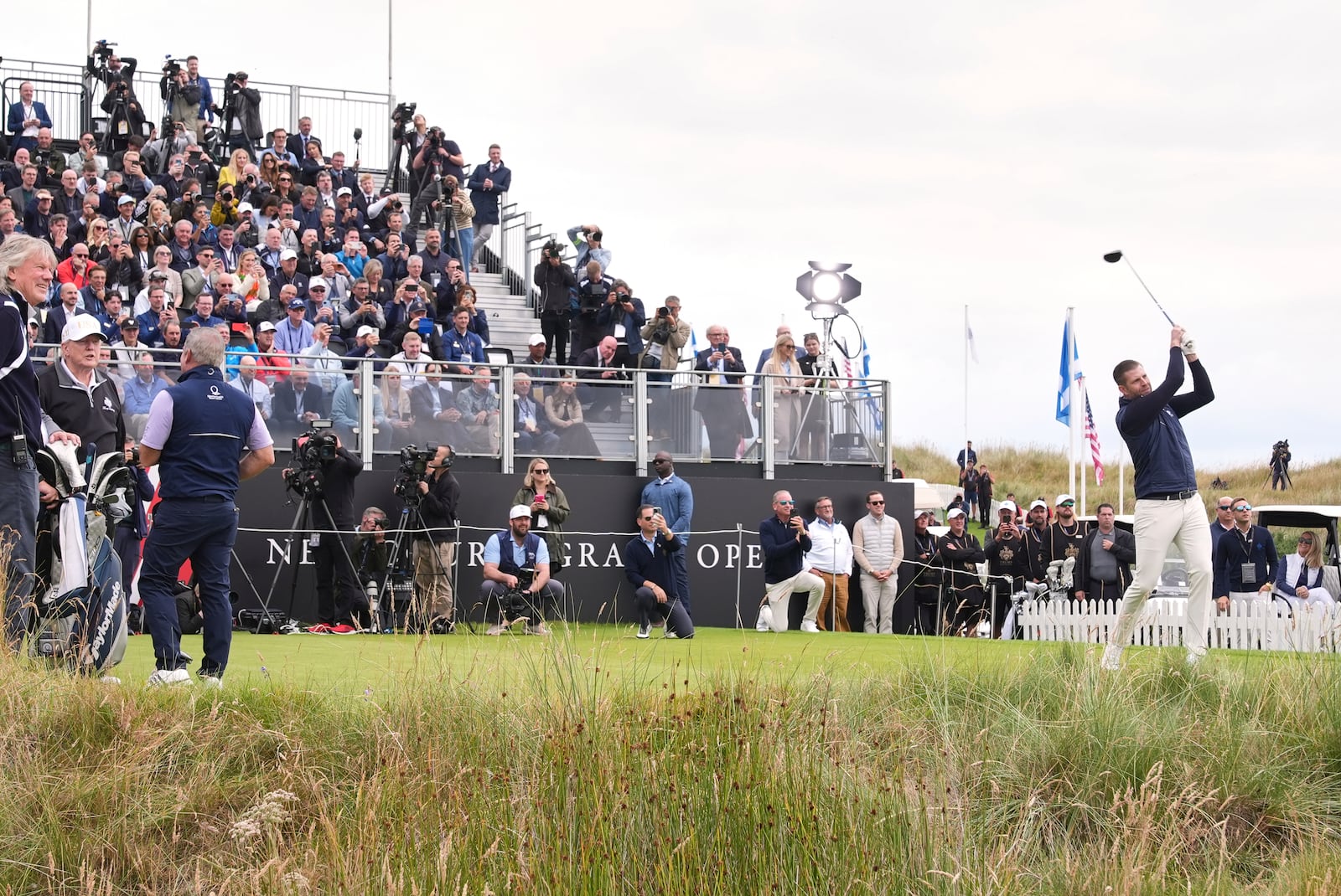 Eric Trump tees off as President Donald Trump, left, stands, during the opening ceremony for the Trump International Golf Links golf course, near Aberdeen, Scotland, Tuesday, July 29, 2025. (AP Photo/Jacquelyn Martin)