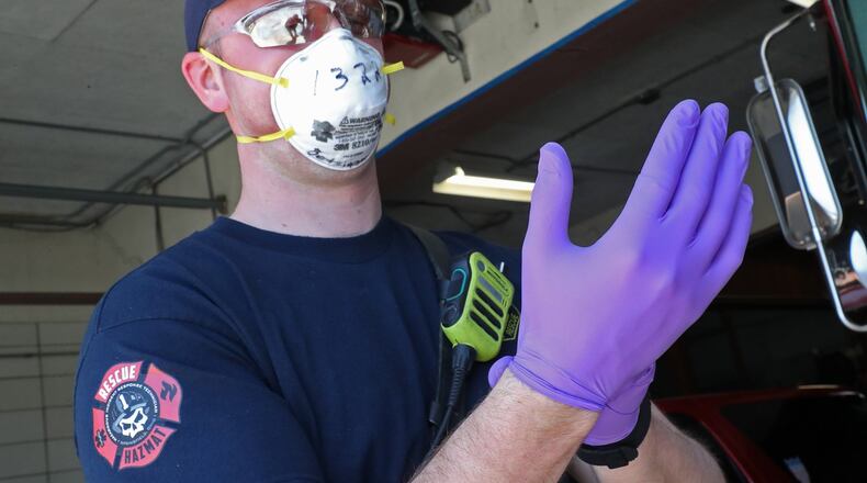 Springfield firefighter Bryon Betsinger puts on his protective equipment before a run in 2021. The lion’s share of local CARES Act funding allocated to the city of Springfield went to cover personnel costs. BILL LACKEY/STAFF
