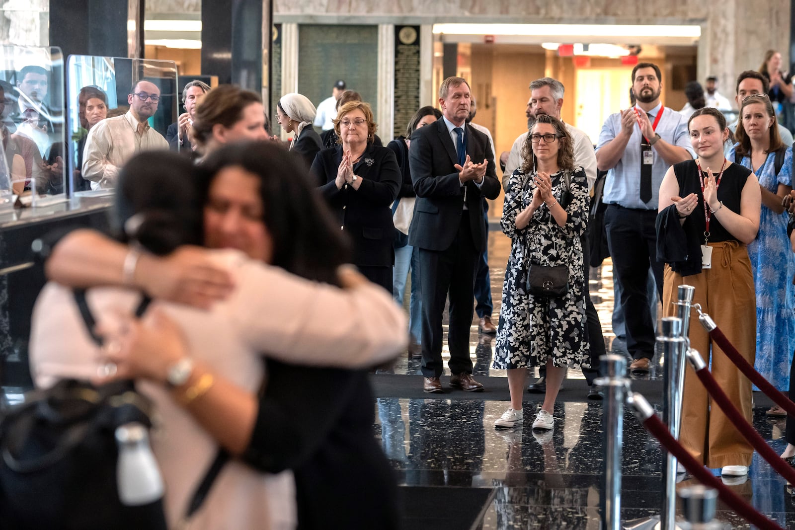 FILE - State Department employees applaud as their colleagues walk through the lobby of the State Department headquarters in the Harry S Truman Building, July 11, 2025, in Washington. (AP Photo/Mark Schiefelbein, File)