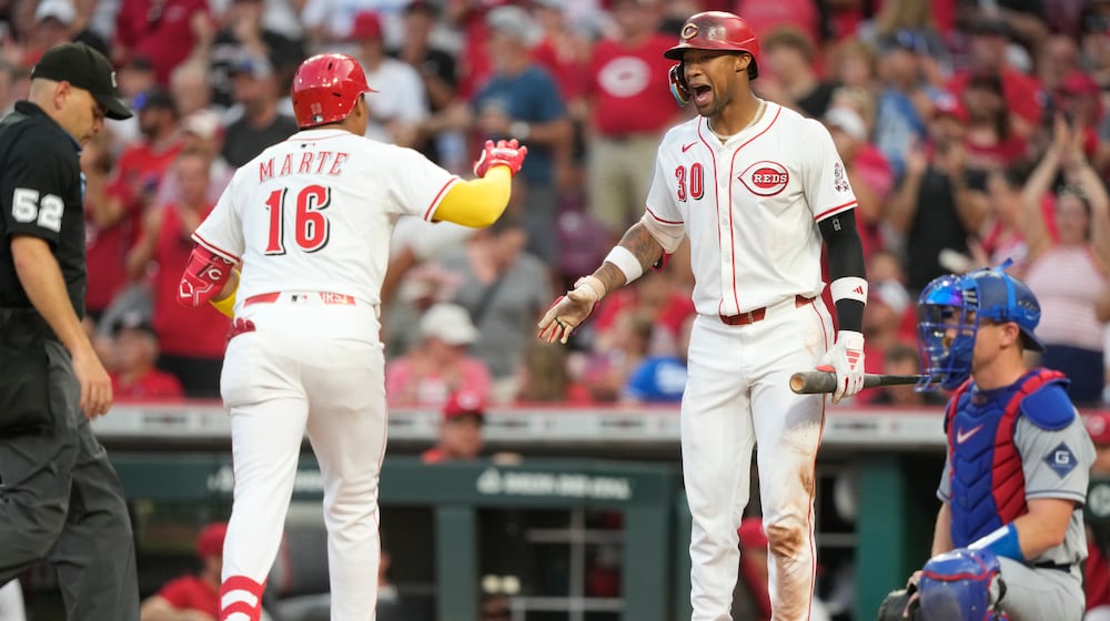 Cincinnati Reds' Noelvi Marte (16) is greeted by Will Benson (30) after Marte hit a solo home run during the fourth inning of a baseball game, Tuesday, July 29, 2025, in Cincinnati. At left is home plate umpire Jansen Visconti (52), and at right is Los Angeles Dodgers catcher Will Smith. (AP Photo/Carolyn Kaster)