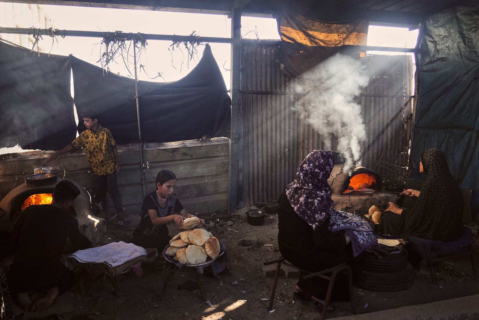 Displaced Palestinians bake bread in a school now serving as a shelter in Deir al-Balah, Gaza Strip Sunday, July 6, 2025. (AP Photo/Abdel Kareem Hana)