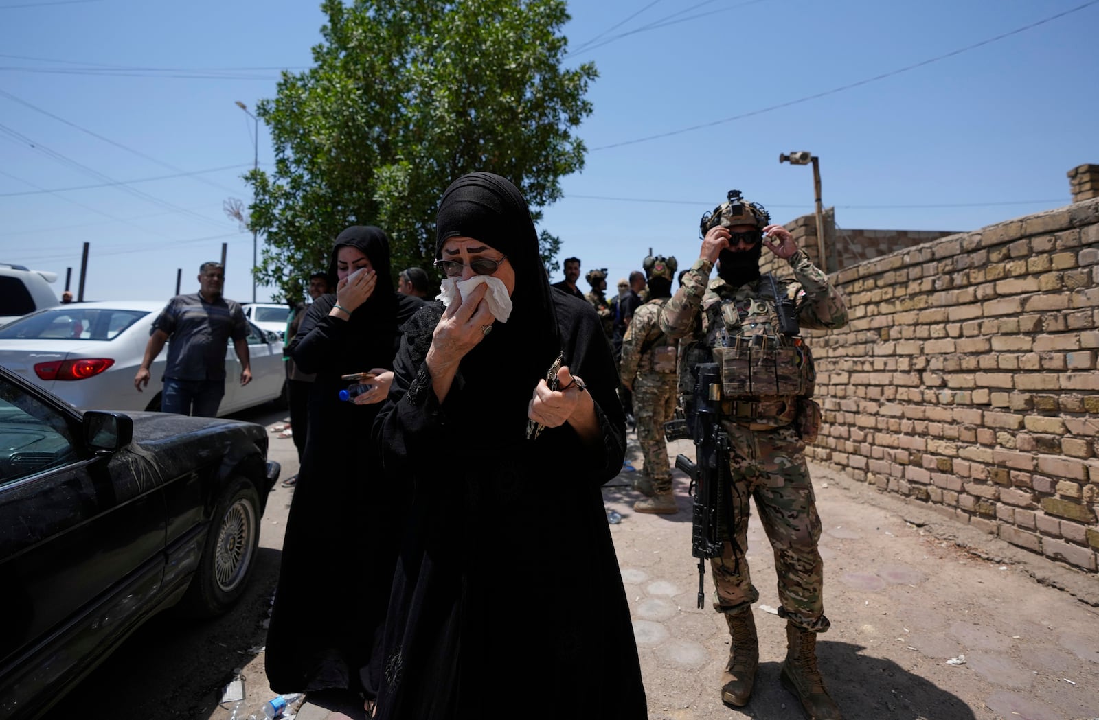 Iraqi people gather in front of a burning hypermarket building in Kut, Iraq, Thursday, July 17, 2025. (AP Photo/ Hadi Mizban)