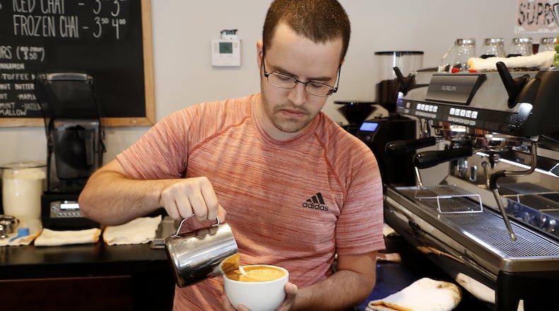 David Tipton makes a customer’s coffee drink at Scout’s Cafe. BILL LACKEY/STAFF