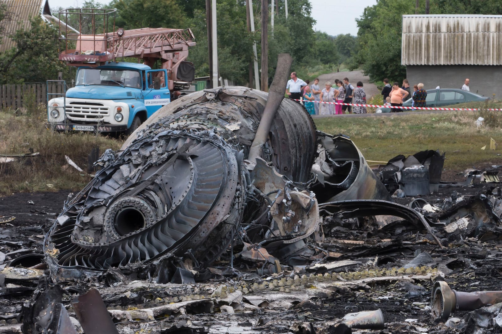 FILE - Local citizens, background, look at the site of a crashed Malaysia Airlines passenger plane near the village of Hrabove, Ukraine, on July 18, 2014. (AP Photo, File)
