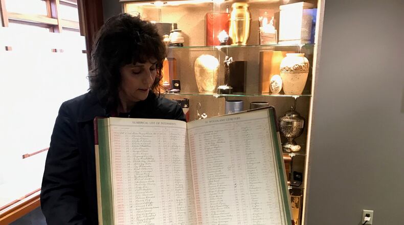 Angie Hoschouer, Manager of Development & Marketing at Woodland Cemetery, holds internment day book showing number of burials from Spanish flu back in 1918. Tom Archdeacon/STAFF