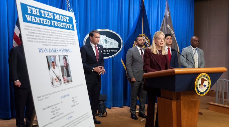 Attorney General Pam Bondi stands near wanted poster for Canadian fugitive Ryan James Wedding as she speaks with reporters during a news conference at the Department of Justice, Wednesday, Nov. 19, 2025, in Washington. (AP Photo/Mark Schiefelbein)